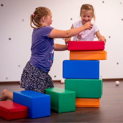 Two girls engaging in imaginative adventures with IGLU Soft Play's Soft Foam Building Blocks - Mini Builder, enhancing their fine motor skills.