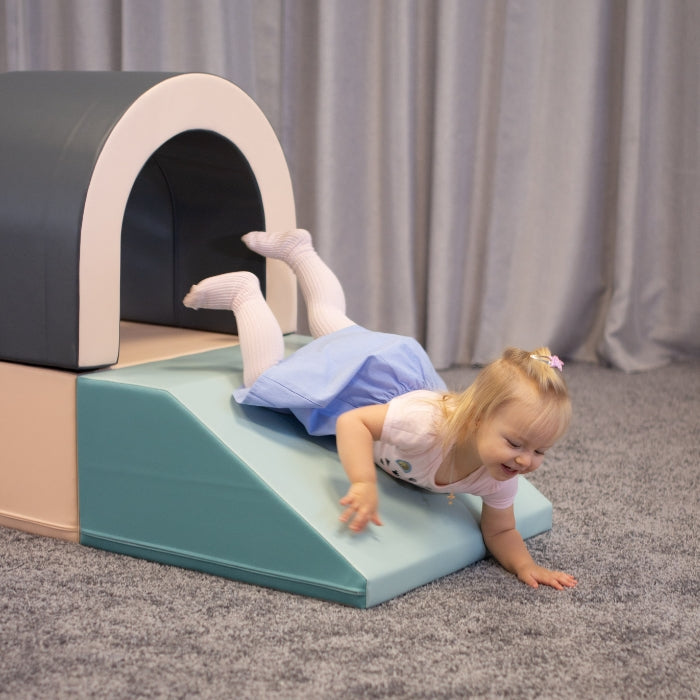 A girl sliding down a soft play foam slide