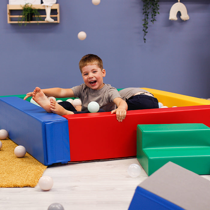 A boy throwing balls from a foam ball pit