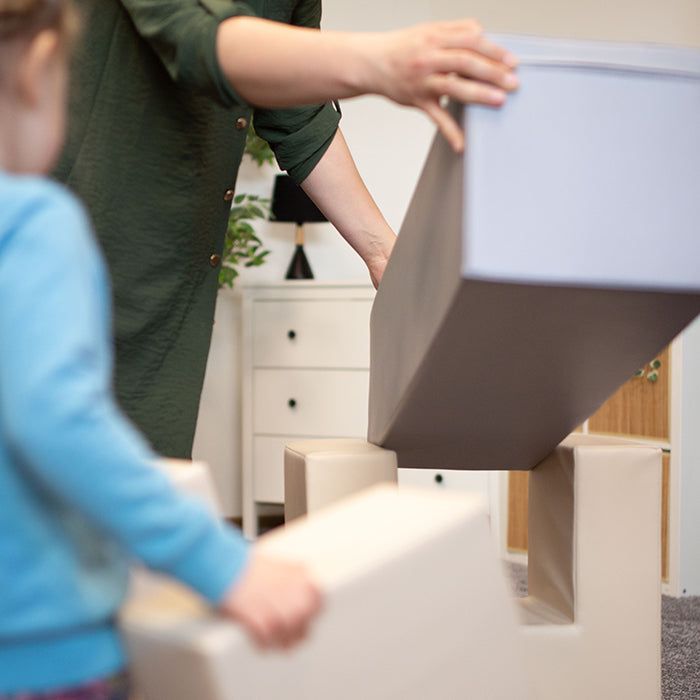 A woman holding an IGLU Soft Play - Soft Play Activity Set - Balance Bridge box in front of a child.