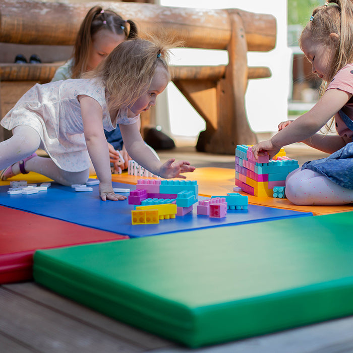 Girls playing with legos on foam mattresses 