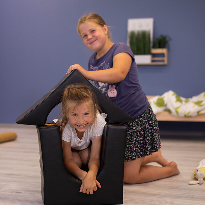 A little girl is exploring imaginative play with the Multifunctional Foam Play Set - Creativity by IGLU Soft Play in a room.