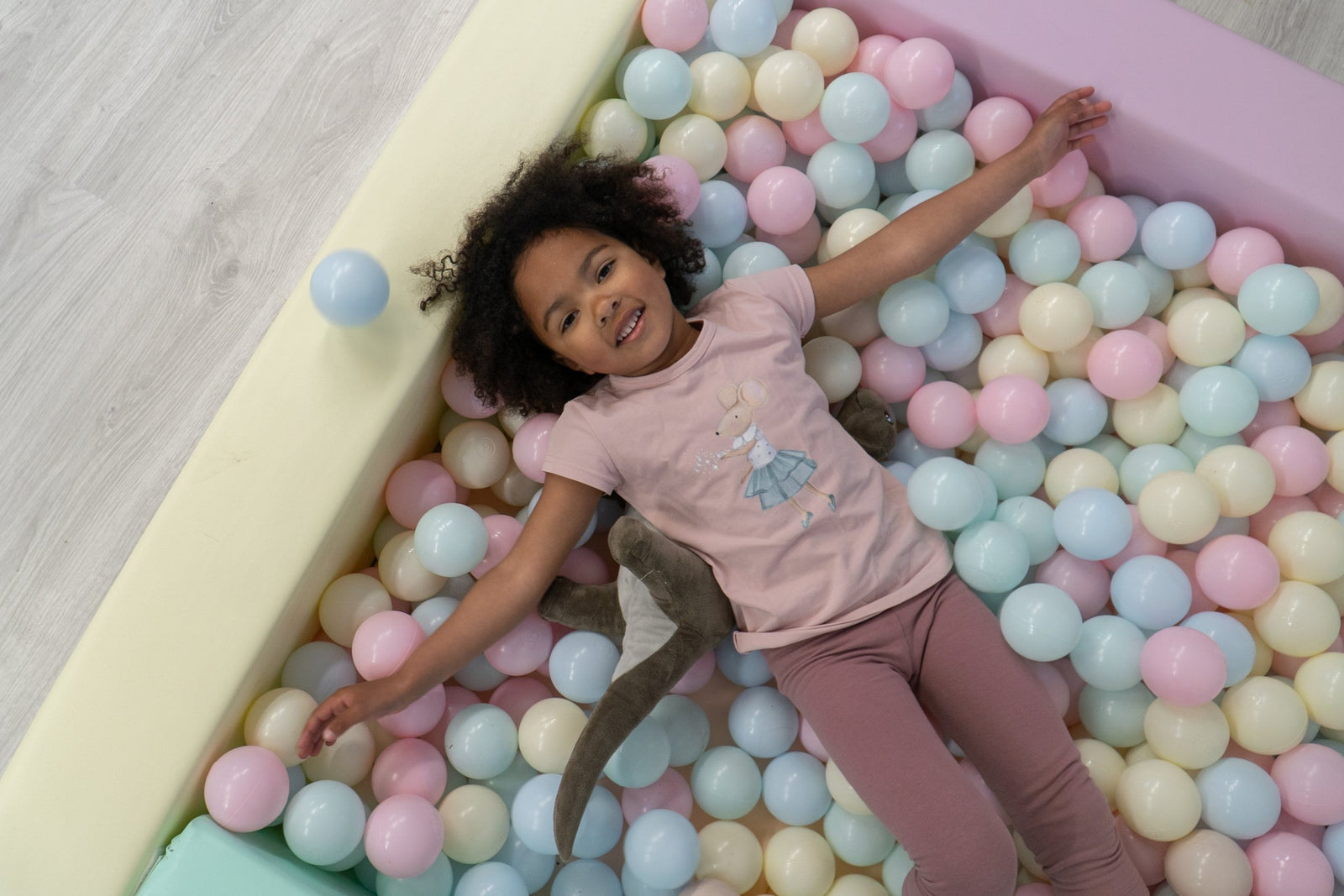 Kind ligt en speelt tussen de pastelballen in de IGLU Square Ball Pit