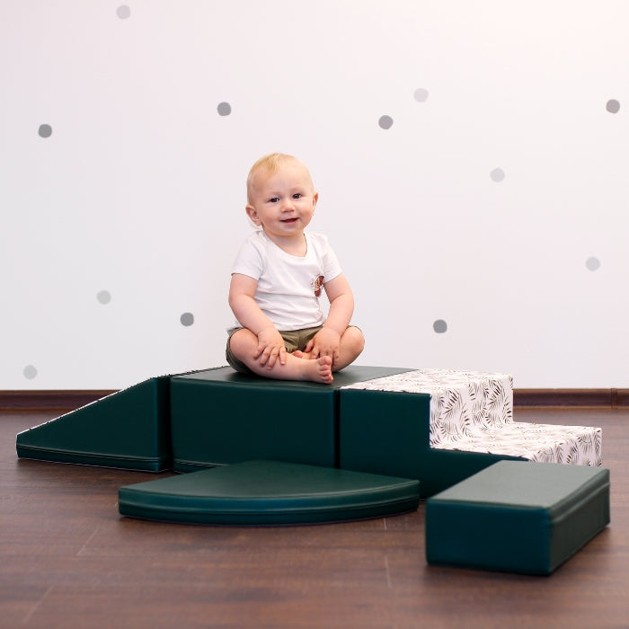 A baby playing with a dark green IGLU set