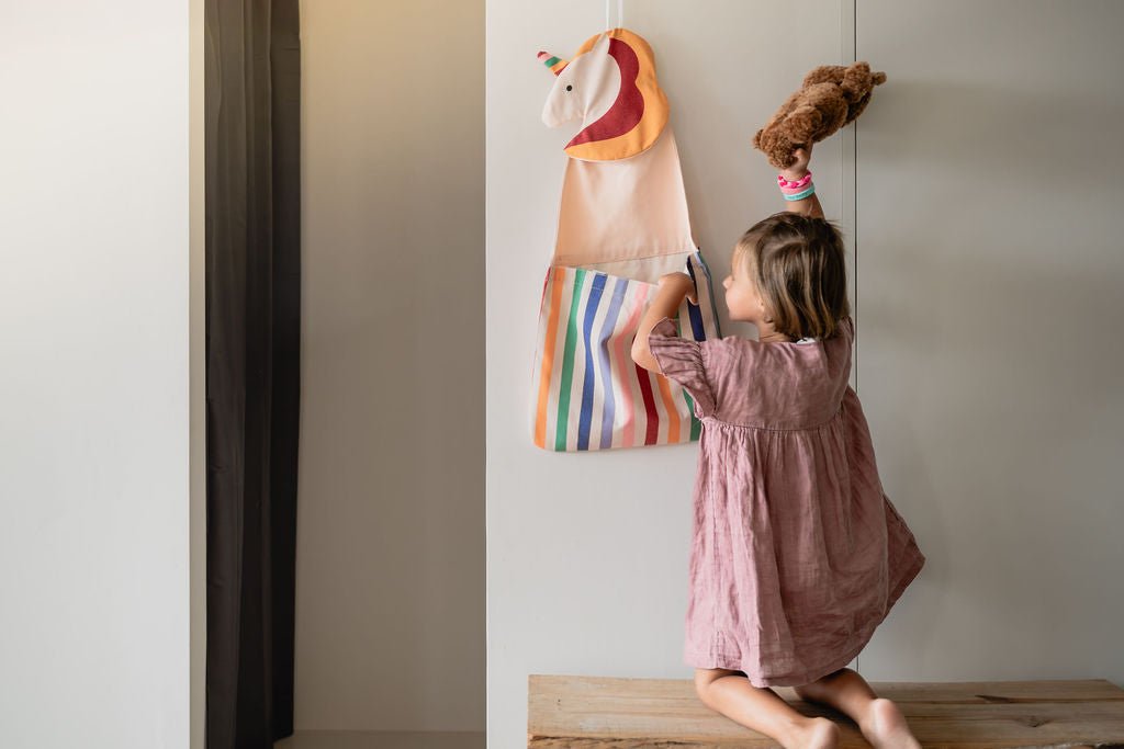 Kind ruimt een knuffel op in de Play&amp;Go Toto Unicorn wandopberger