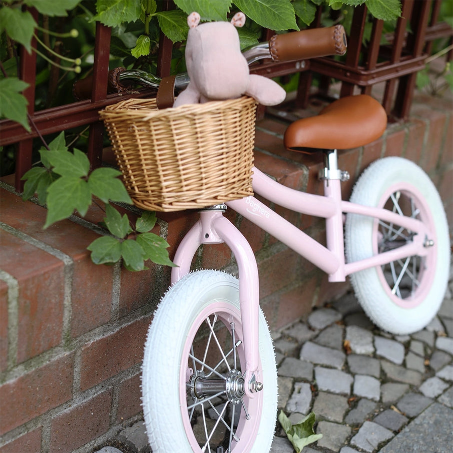Rosa Vintage-Laufrad mit Weidenkorb